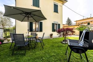 un patio con mesa, sillas y sombrilla en Hostly-Garden House Metato-Apartment with Garden, 15min from sea, en Fiocina