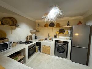 a kitchen with a refrigerator and a washing machine at Tazuri Surf House in Taghazout