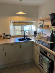 a kitchen with a sink and a stove at The Wharfe at Greystones - Cosy, comfortable retreat in Buckden