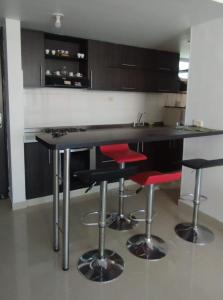 a kitchen with a black counter and red stools at Apartamento mirador de la sierra 2 in Valledupar