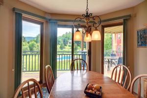 a dining room with a table and a large window at Jardin du Village by Chez Tremblant in Mont-Tremblant