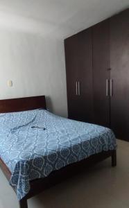 Schlafzimmer mit einem Bett mit blauer Decke und Holzschränken in der Unterkunft Apartamento mirador de la sierra 2 in Valledupar