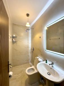uma casa de banho com um lavatório, um WC e um espelho. em Hotel Nature em Kolonjë