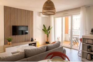 a living room with a couch and a television at Le Candle - Parking & Balcon - Muret - Toulouse in Muret
