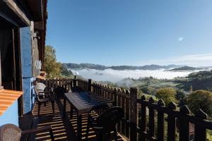 una mesa y sillas en un balcón con un valle nublado en APARTAMENTOS EL CORITU en Nieda