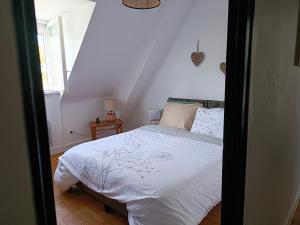 a bedroom with a bed with white sheets and a window at Vue unique sur le Mont St Michel in Huisnes-sur-Mer