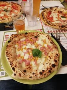 eine Pizza auf einem grünen Teller auf einem Tisch mit anderen Pizzen in der Unterkunft Casa Palinuro Vacanze in Palinuro