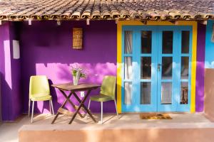 ein lila und blaues Haus mit einem Tisch und Stühlen in der Unterkunft Pousada Barari in Guarapari