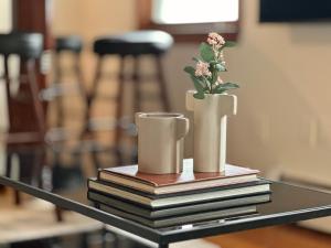 uma mesa com livros e um vaso com uma planta em cima em AO Destinations - Wooster Street in Little Italy New Haven em New Haven