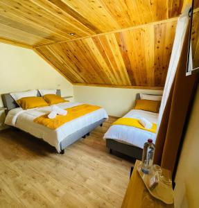 two beds in a room with a wooden ceiling at Au sommet des Salazes in Salazie