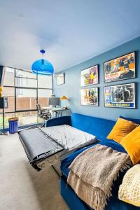 Unique Flat with Pool in Trendy Peckham Area في لندن: غرفة زرقاء مع سرير ومكتب