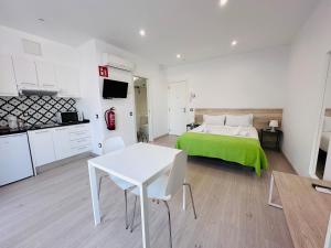 1 dormitorio con cama verde y mesa blanca en Rainbow Apartments BY BLAUSITGES, en Sitges