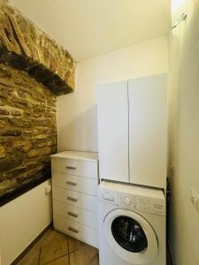 a laundry room with a washing machine and a stone wall at Giulivi Assisi Apartments in Assisi