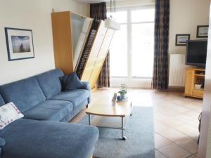 ein Wohnzimmer mit einem blauen Sofa und einem Tisch in der Unterkunft Villa Hildegard Appartement 8 in Binz