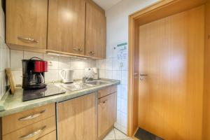 uma cozinha com armários de madeira, um lavatório e uma porta em Strandhotel, App 1SH109 em Heiligenhafen