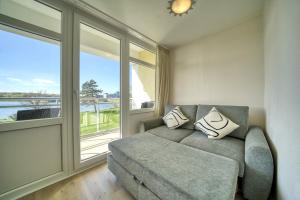 uma sala de estar com um sofá e uma grande janela em Strandhotel, App 1SH109 em Heiligenhafen