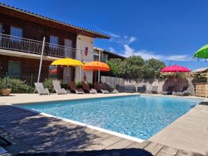 a swimming pool with chairs and umbrellas at Hotel Le Vanséen in Les Vans