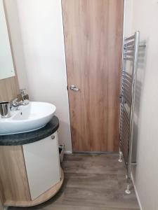 a bathroom with a sink and a wooden door at Lovely 3-Bed Lodge in Eyemouth with stunning views in Eyemouth