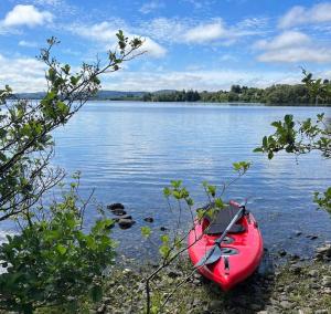 un kayak rojo sentado a orillas de un lago en Private apartment ONE on Lough Corrib, Oughterard en Galway