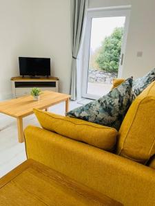 uma sala de estar com um sofá amarelo e uma mesa em Private apartment ONE on Lough Corrib, Oughterard em Galway