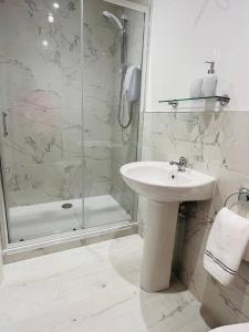 biała łazienka z umywalką i prysznicem w obiekcie Private apartment ONE on Lough Corrib, Oughterard w Galway