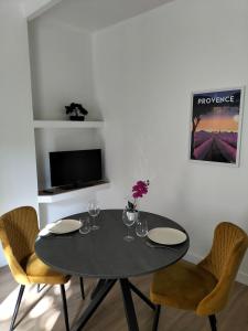a dining room with a table with chairs and a tv at Studio climatisé intra muros balcon in Avignon