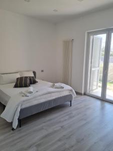 Dormitorio blanco con cama y ventana grande en Casa Viky, en Bari Palese