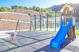 um parque infantil com um escorrega azul e baloiços em Highest penthouse with best skyline & sea views em Benidorm