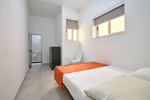 um quarto branco com uma cama e uma cadeira em Seafront Apartment in Xemxija em St. Paul's Bay