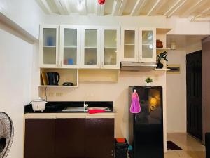 a kitchen with white cabinets and a black refrigerator at RAYMONDS LODGE in Manila