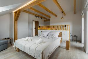 Schlafzimmer mit einem großen weißen Bett mit einem Kopfteil aus Holz in der Unterkunft Apartamenty TAFLA nad Jeziorem Czorsztyńskim in Kluszkowce