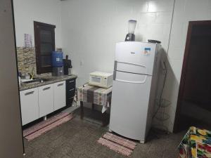 La cuisine est équipée d'un réfrigérateur blanc et d'un four micro-ondes. dans l'établissement Chácara Charbella, à Três Ranchos