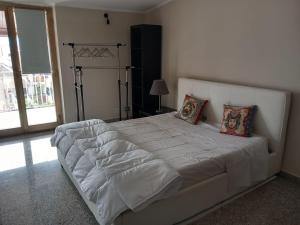 um quarto com uma cama grande com lençóis brancos e almofadas em Bluesky apartment em Giardini Naxos