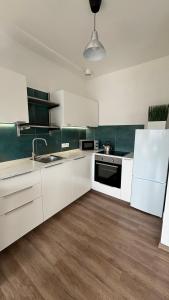 a kitchen with white cabinets and a sink and a refrigerator at TRIO apartment in Piešťany