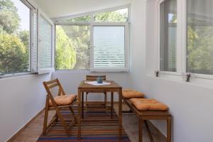 einen Tisch und Stühle in einem Zimmer mit Fenstern in der Unterkunft Ferienwohnung für 4 Personen ca 65 m in Njivice, Kvarner Bucht Krk in Njivice