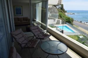 un balcone con tavolo e sedie in vetro e una piscina di Pura Vida - apartamento con salida a la costa a Concón