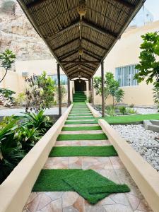 a walkway leading to a building with grass at FIG SHADES مزرعة ظلال التين in Ţīwī