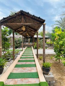 a walkway in a garden with a wooden structure at FIG SHADES مزرعة ظلال التين in Ţīwī