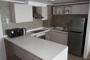 una cucina con bancone bianco e frigorifero di Pura Vida - apartamento con salida a la costa a Concón