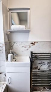 a white bathroom with a sink and a mirror at Spacious flat on Breck Road! in Liverpool