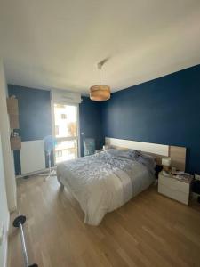 een slaapkamer met een blauwe muur en een bed bij Appartement confort in Garches