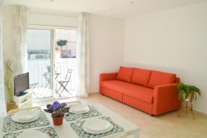 uma sala de estar com um sofá vermelho e uma mesa em Nova Apartment by Hello Homes Sitges em Sitges