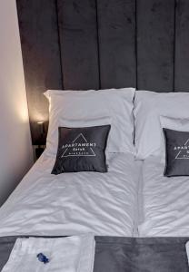 a bed with white sheets and two pillows on it at Apartament Sztuk Pięknych 4 in Piła