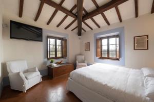 a bedroom with a bed and a tv and two chairs at LA FORNACE in Asciano