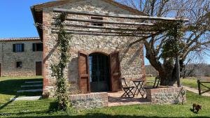 a small stone building with a door in the grass at LA FORNACE in Asciano