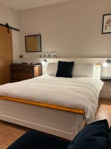 a large white bed with a black pillow on it at The Snug at Caphays: perfect rural retreat in Long Burton