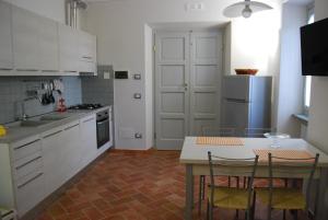 una cocina con armarios blancos y una mesa con sillas. en Casa Girella, en Terontola