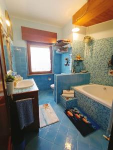ein blaues Badezimmer mit einer Badewanne und einem Waschbecken in der Unterkunft Villa Sabry in Turriaco