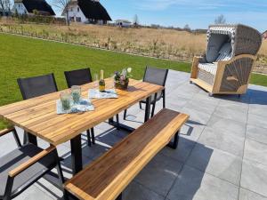 una mesa de madera y sillas en un patio en Reethaus Edith im Süden der Insel Rügen am Naturschutzgebiet - Eine Auszeit für Körper und Seele, en Mellnitz