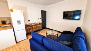 a living room with a blue couch and a kitchen at Spacious flat on Breck Road! in Liverpool